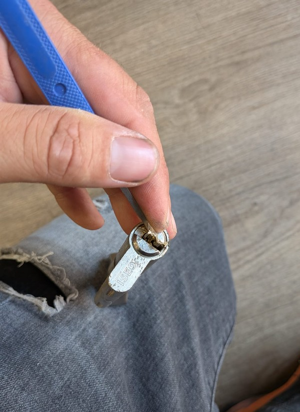 Extraction d'une clé cassée dans un cylindre ISEO à Nîmes : serrurier au travail avec outil spécialisé.
