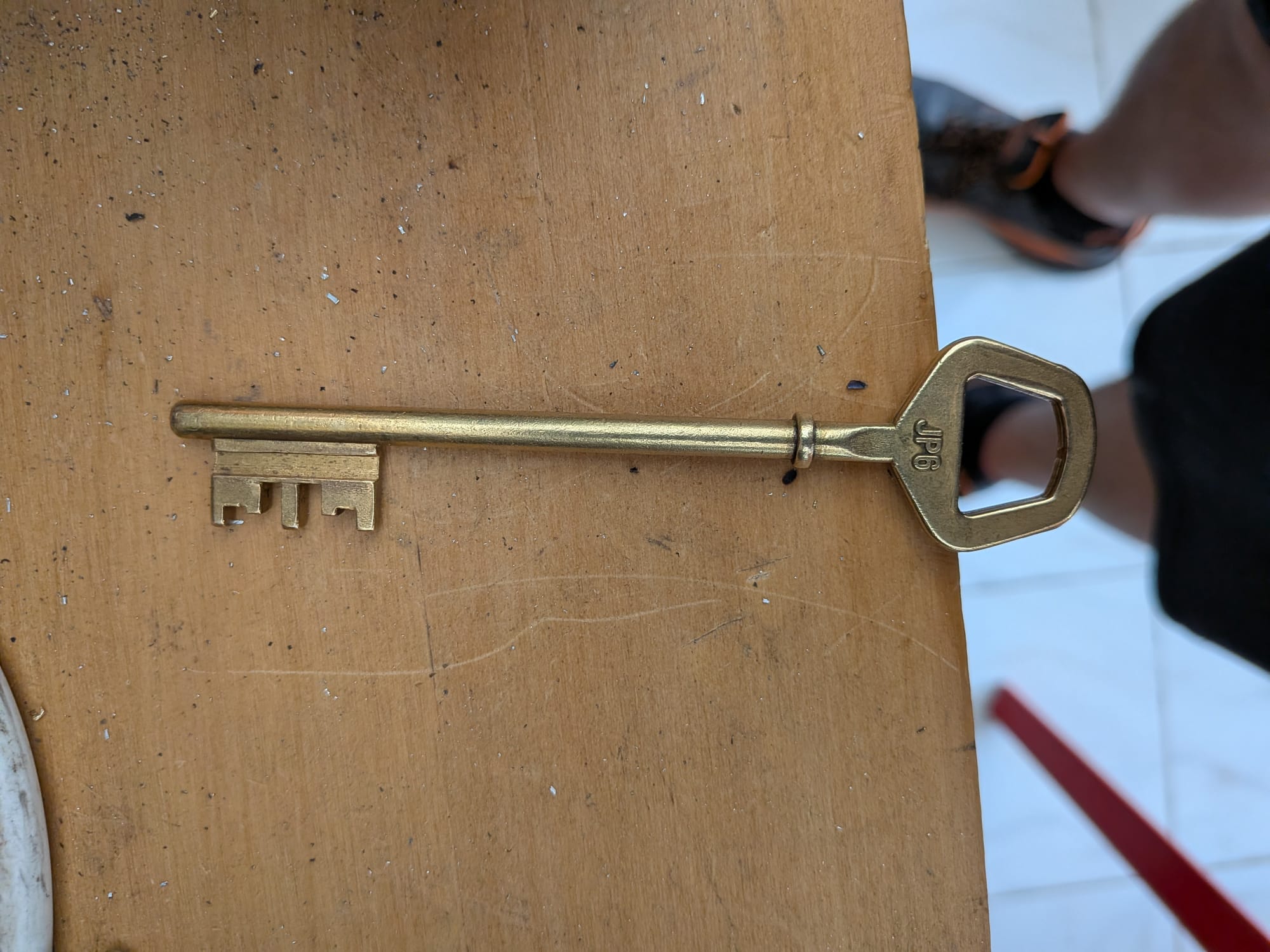 Clé à gorge en laiton avec panneton découpé, posée sur l'établi de l'atelier à Nîmes.