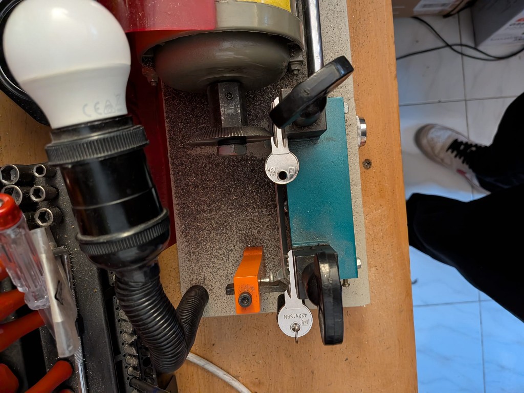 Machine à dupliquer les clés : clé modèle et brut alignés sous éclairage de travail.