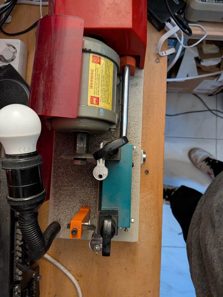 Détail d’une machine de reproduction de clés en cours d’utilisation, copeaux métalliques visibles.