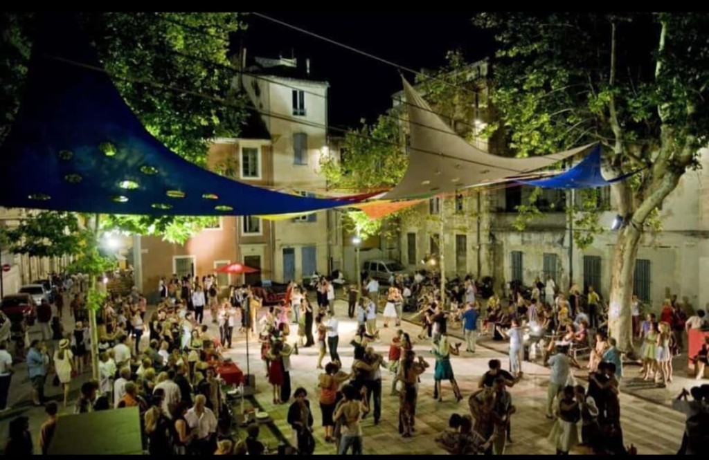 Place animée en soirée à Nîmes : bodega, danse et foule festive pendant la feria.